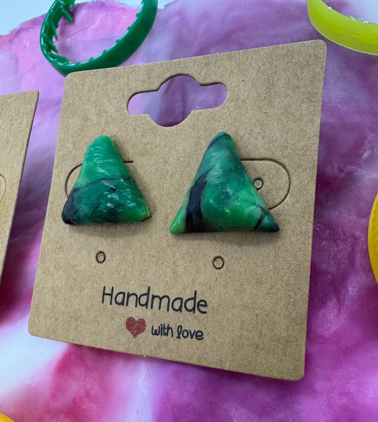 Green triangle-shaped earrings on a 'Handmade with Love' card against a colorful background.