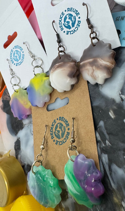 Colorful earrings on a wooden stand with a gray marble background