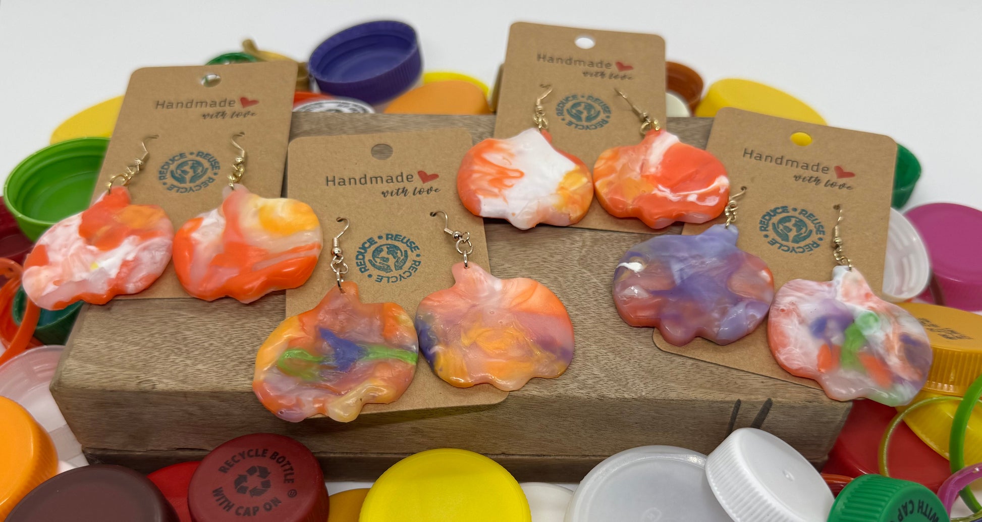 Colorful earrings on display with various bottle caps and lids.