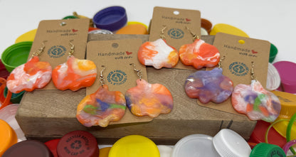 Colorful earrings on display with various bottle caps and lids.