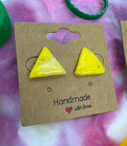 Yellow triangle-shaped earrings on a brown card with 'Handmade with Love' text, on a pink and white marbled background.