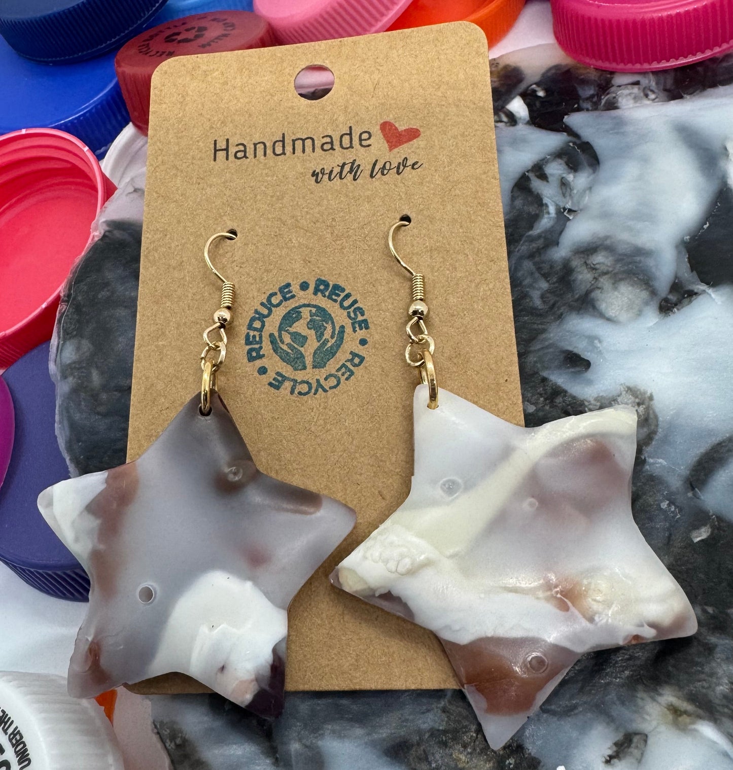 Jewelry with a 'Handmade with Love' tag on a background of colorful bottle caps.