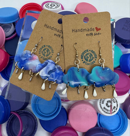 Blue and white ceramic hair clips on a cardboard backing with a 'Handmade with Love' label, surrounded by colorful bottle caps.
