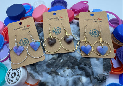 Heart-shaped earrings on display with a brand logo against a colorful background.