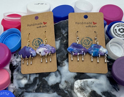 Pair of earrings on cards with colorful bottle caps in the background