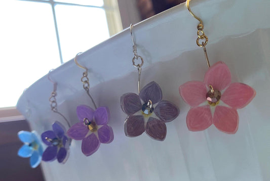 Flower-shaped earrings on a white surface with a blurred background
