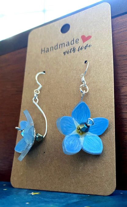Blue flower-shaped earrings on a 'Handmade with Love' card.