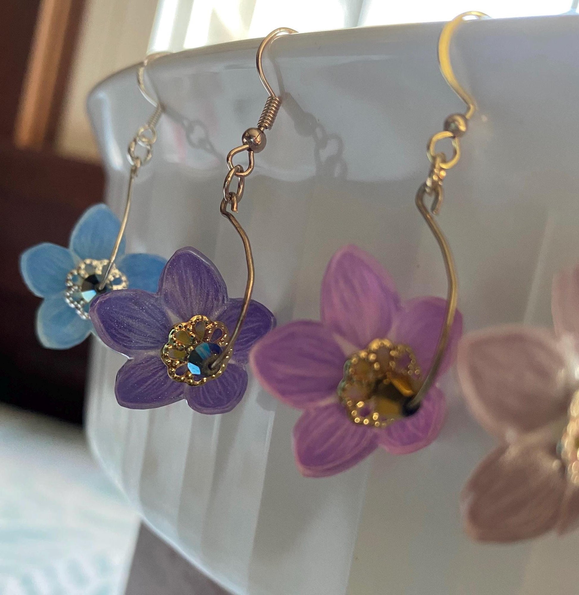 Flower-shaped earrings with purple and gold details on a white surface.
