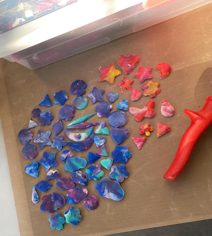 Colorful star-shaped objects on a brown surface with a red tool.
