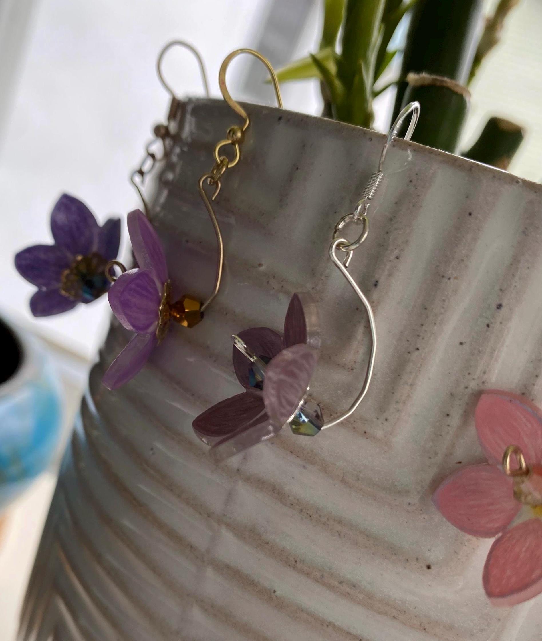 Pair of earrings with floral designs on a textured surface