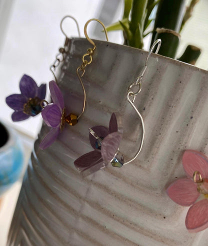 Pair of earrings with floral designs on a textured surface